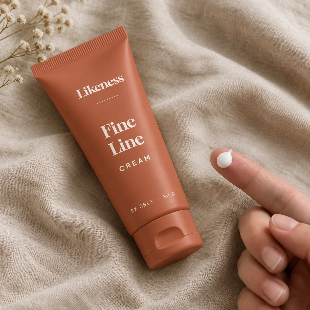 Fine Line Cream tube on linen with a pea-sized amount on a fingertip